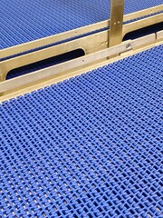 A close-up of a blue polyurethane belt in modular industrial conveyor system. Stainless steel...
