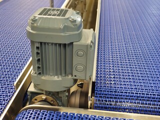 Electric motors in the stainless steel conveyor system with polyurethane, modular belt. Transport systems in industrial factories.