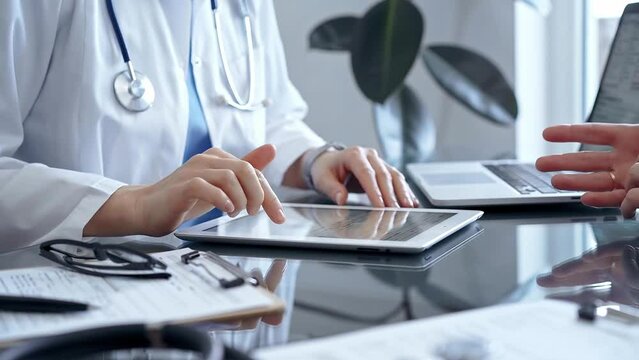 Doctor and patient conversation with tablet computer in clinic office. Medicine and Health care