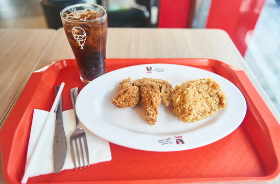Danang, Vietnam - 06.27.2023: Lunch at a fast food cafe. KFC wings on a plate of Coca-Cola. High quality photo