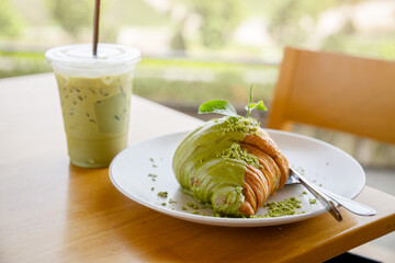 Matcha green tea with croissant on the wooden table at Choui Fong tea plantation in Chiang Rai province, Thailand - obrazy, fototapety, plakaty