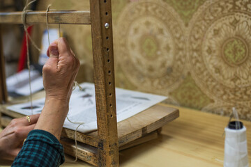 A woman's hands binding a book with the old method on an antique device.