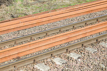 Railroad background. Railway perspective. Train track landscape. Old railroad concrete tie. Track ballast gravel made of crushed stone. Rusty rail. New route construction.