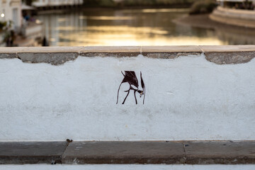 Graffiti with a sexy lady in a mini skirt on the bridge in Tavira - background - river and...