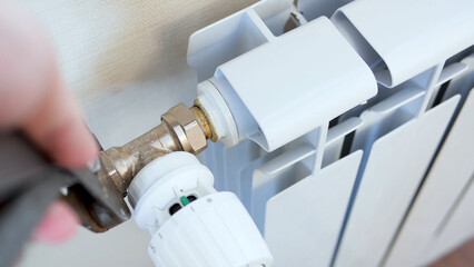 Plumber's hands install a radiator with a two wrench. Man installing radiator valve