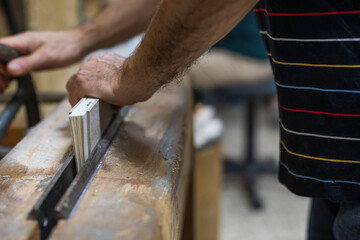 Older man's hands binding a book on an antique workbench.