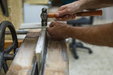 Elderly man's hands hammering on antique worktable