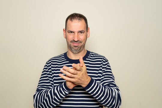 Bearded Hispanic man in his 40s feeling proud, mischievous and arrogant while plotting an evil plan or thinking of a trick. Isolated on beige studio background.