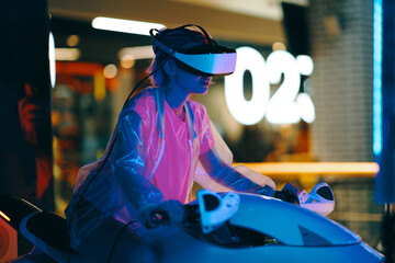 A young woman plays motorcycle racing in virtual reality while sitting on a motorcycle.