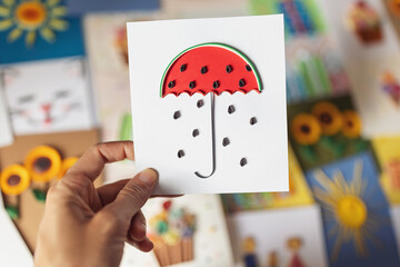Hand holding quilling card watermelon umbrella with rain of seeds. Symbol of summer and fresh...