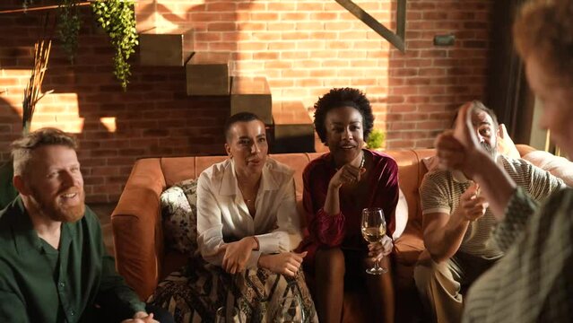 Diverse group of friends laughing and and playing charades at home gathering