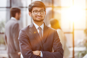 Handsome young business man in glasses standing confidently in the office