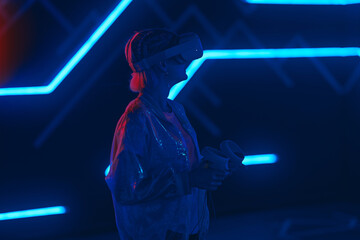 Young woman playing VR game in neon room.