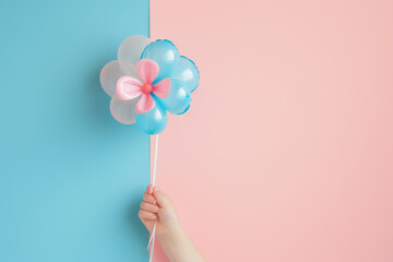 child's hand holding a flower-shaped balloon with blue and pink details against a two tone background