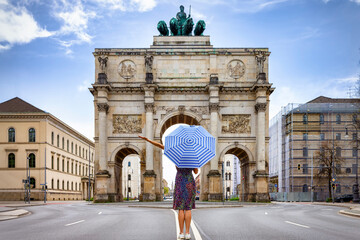 Munich travel concept with a tourist woman holding an umbrella in front of the Victory Gate, Germany - 776357177