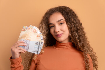 joyful young woman with money, brazilian real in beige colors. economy, payment, successful concept.  - obrazy, fototapety, plakaty