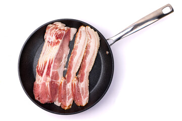 Top down view of slices of bacon not yet cooked in a black frying pan isolated on white
