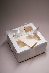 white cake with hearts in a white cardboard box tied with ribbon. Delivery of sweets and gifts