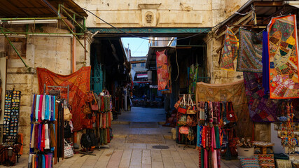 The alleys of Jerusalem's market brim with vibrant tapestries and an array of colorful fabrics, reflecting the rich cultural tapestry of the city.