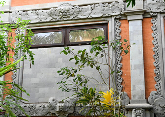Balinese Plaster Decorations Around Window Frame on Brick Building with Flowering Vines