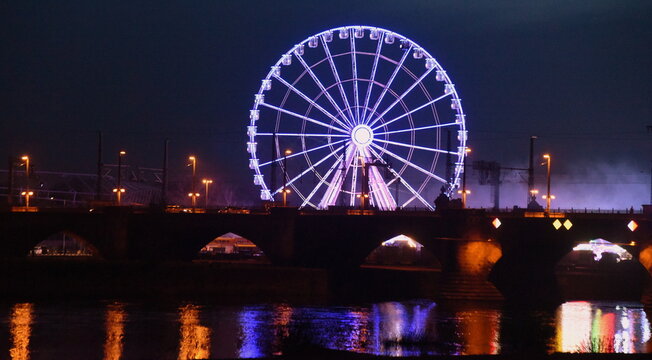 Beleuchtetes Riesenrad vor Nachthimmel am Ufer der Elbe