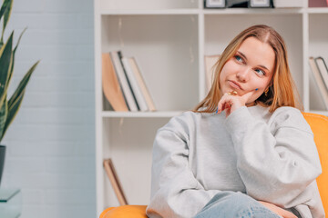 portrait of young blue eyed blonde woman or student at home thinking