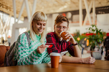 Happy friends sitting at cafe, drinking coffee and shopping online.