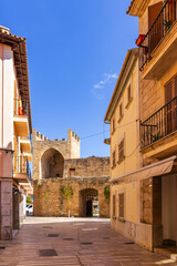Street in Alcudia old town leading to the stone gate Porta del moll in Mallorca, Spain, Balearic Islands - obrazy, fototapety, plakaty