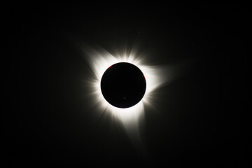 Total solar eclipse, with the moon covering the sun, surrounded by a glowing corona.