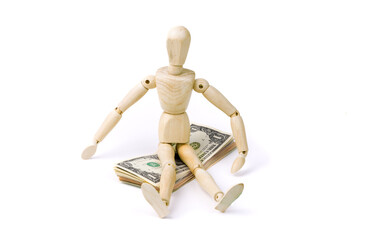 A wooden mannequin sitting on a pile of dollar bills suggesting the finance strategy of sitting on cash
