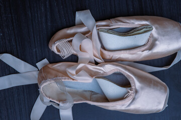 Close-up of Pair of used Ballet pointe shoes. Ballet dance slippers with a bow of ribbons on a dark...