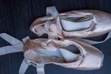 Crédence de cuisine en verre imprimé École de danse Close-up of Pair of used Ballet pointe shoes. Ballet dance slippers with a bow of ribbons on a dark background. Gray dark background. Top view.