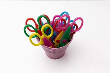Collection of vibrant, multi-colored children's scissors arranged in a small purple container