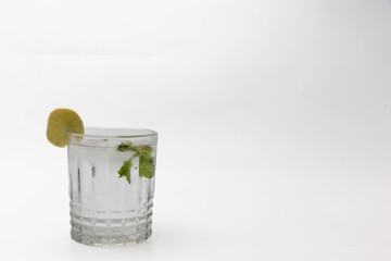 Crystal clear glass of water with lemon slice and mint on white background