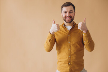 Portrait of modern millennial bearded man happy and smiling in yellow shirt showing beehive fingers
