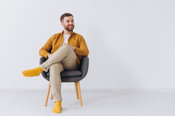 Modern happy smiling millennial man in a yellow shirt on white background