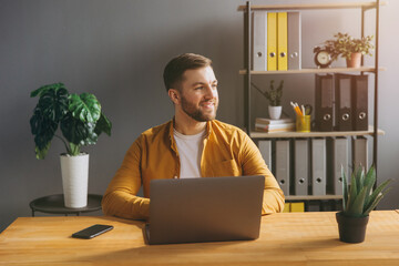 Portrait of a modern businessman man in a yellow shirt working on a laptop in the office