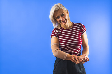 young woman with a bandage on her elbow for support, blue background. High quality photo