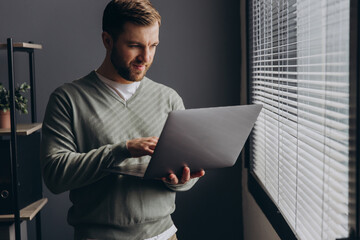 Modern bearded businessman holding laptop in the office
