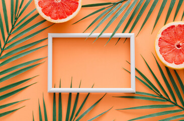 Creative trendy summer composition made of grapefruit and tropical green palm leaves with white...