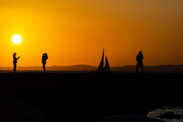 Fototapeta premium People, in silhouette, are seen on the Porto da Barra pier enjoying the sunset in the city of Salvador, Bahia.