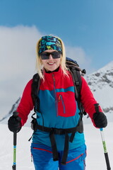 A professional woman skier rejoices after successfully climbing the snowy peaks of the Alps - 776497151