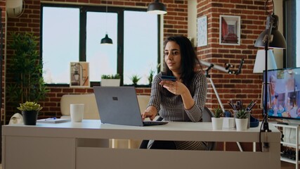 Smiling woman stoked on doing online shopping, carefully typing debit card information on laptop...