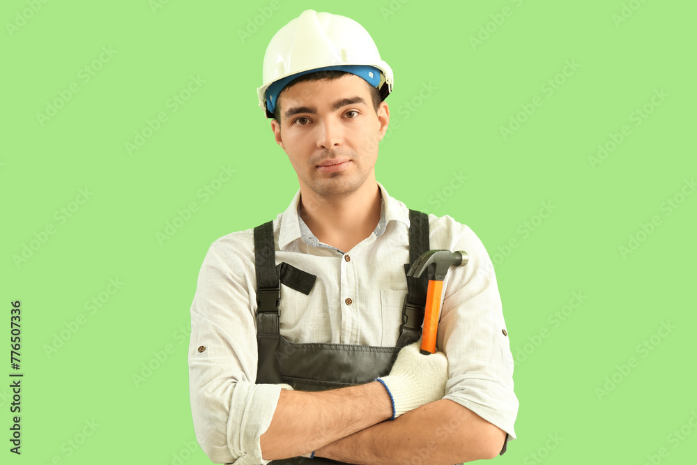 Wall mural Young carpenter with file and hammer on green background