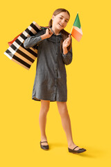 Little girl with flag of Italy and shopping bags on yellow background