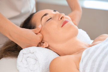Fototapeta na wymiar Beautiful mature woman receiving face massage in spa salon
