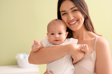 Happy mother with cute little baby in room at home