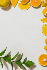 natural frame made with slices of oranges and mandarin limes and a twig of green leaves on white space background