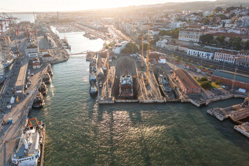 Aerial drone shot ship repair dry dock in Lisbon's port, situated on the north bank of the Tagus River. The shipyard is a key facility at the heart of Lisbon harbor.