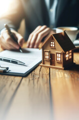 Vertical real estate photo Man signing documents next to a miniature house, illustrating the concept of fulfilling the dream of buying a house with savings. Copy space at the bottom